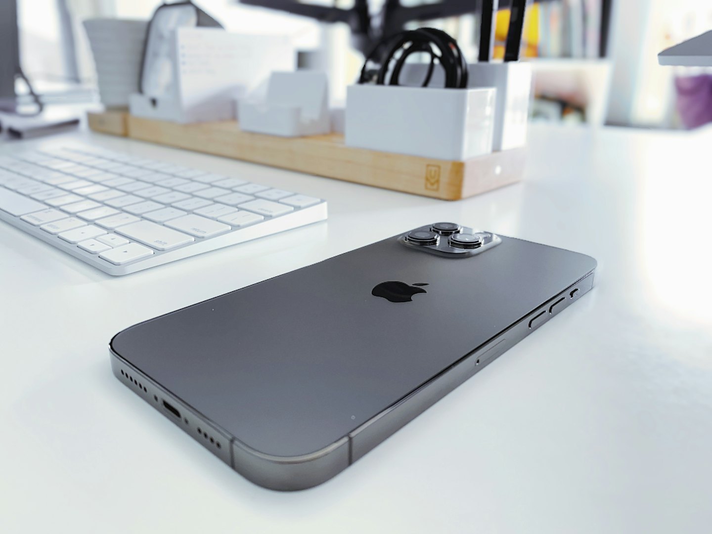 Dark grey iPhone lies face down on a white desk.