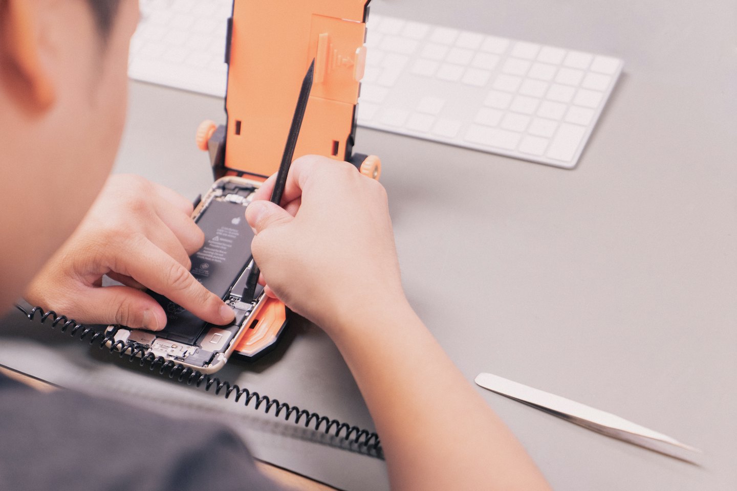 Technician's hands repairing an open smartphone with tools.